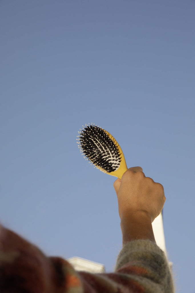 Brosse à cheveux mixte jaune dans une main
