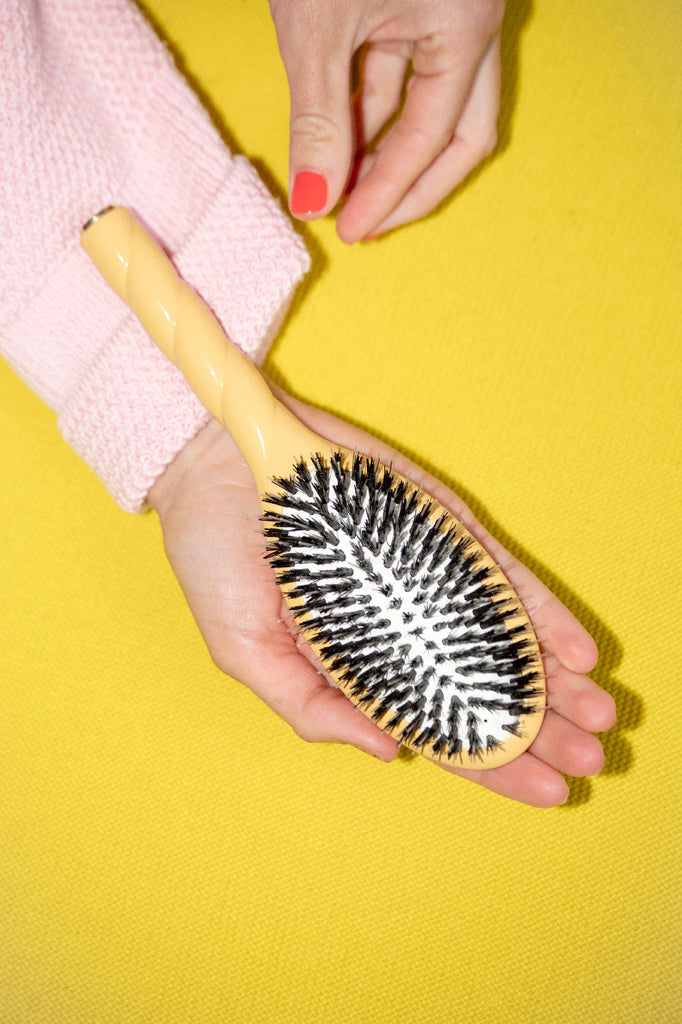 Brosse en poils de sanglier jaune dans une main